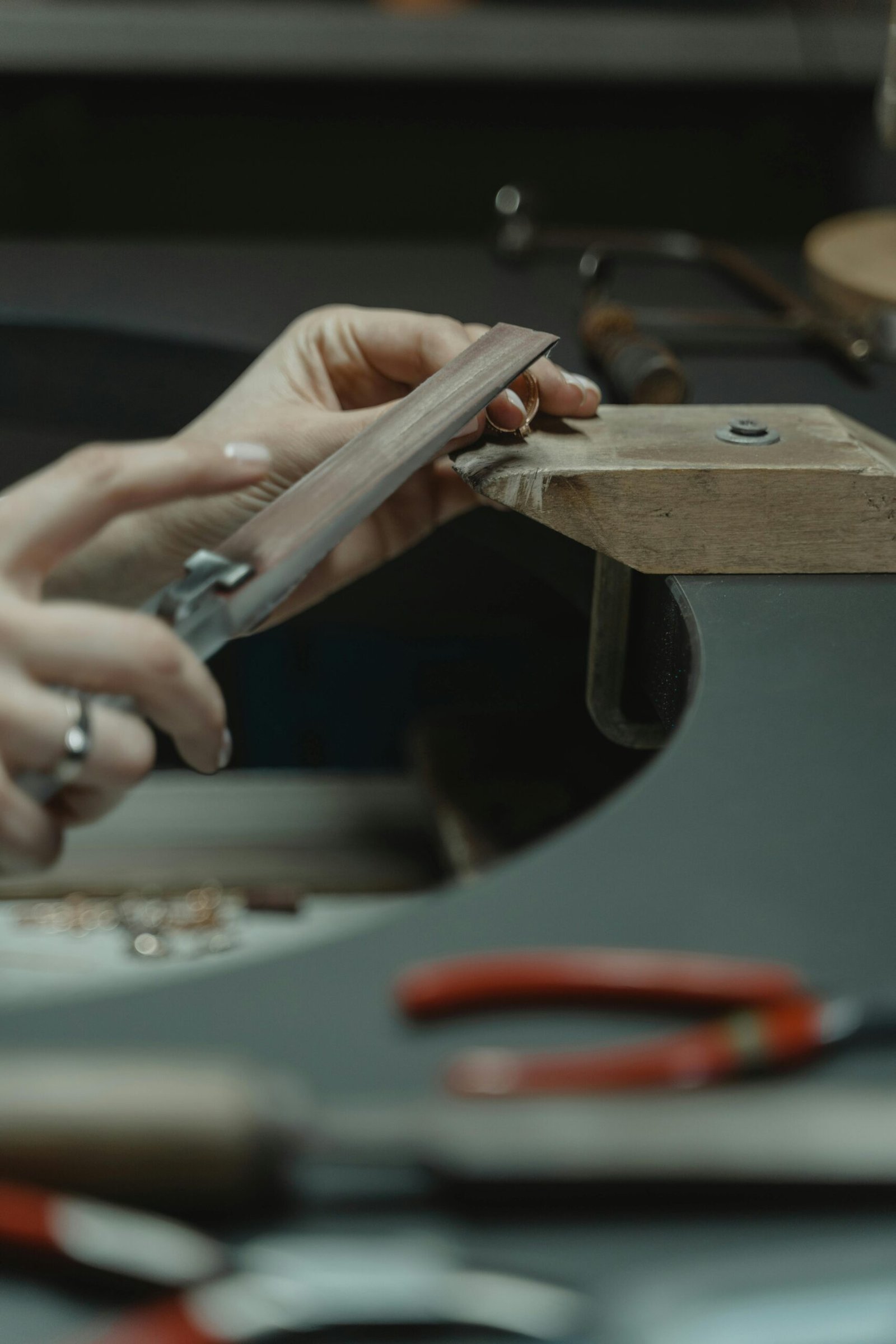 Close-up of a jeweler using a file on metal, crafting delicate jewelry pieces in an artisan workshop.